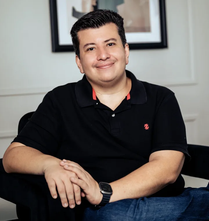Wesley Willians sentado, sorrindo, de camisa polo preta